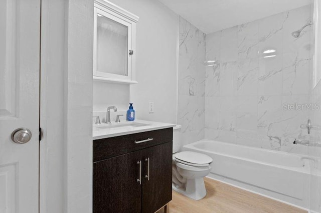 full bathroom featuring vanity, tiled shower / bath combo, hardwood / wood-style flooring, and toilet