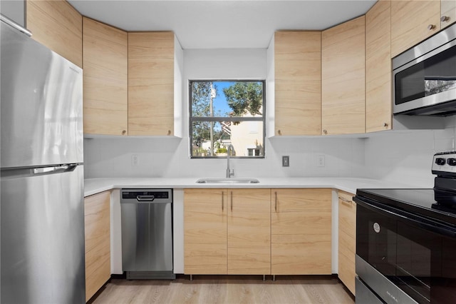 kitchen with appliances with stainless steel finishes, light brown cabinets, and sink