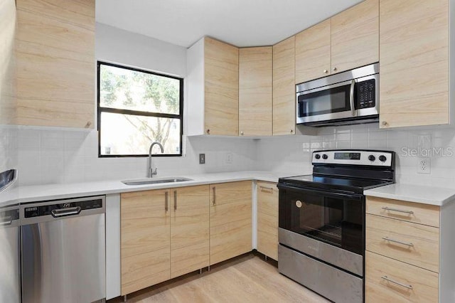 kitchen with appliances with stainless steel finishes, sink, light wood-type flooring, backsplash, and light brown cabinets