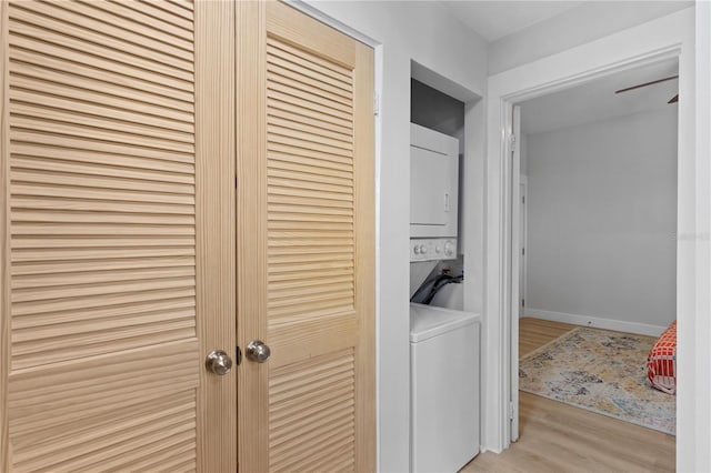 clothes washing area featuring light hardwood / wood-style floors and stacked washing maching and dryer