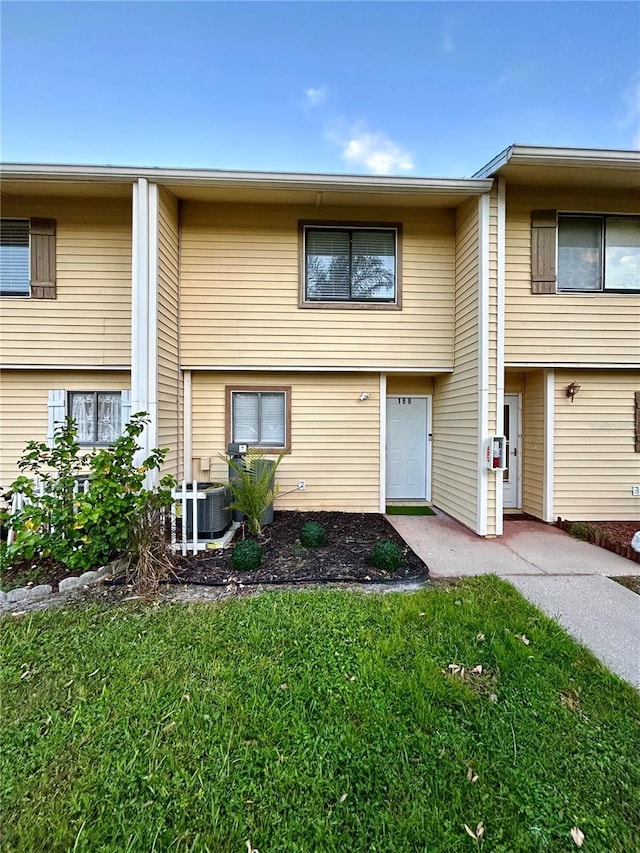 view of front of home with a front yard and central AC