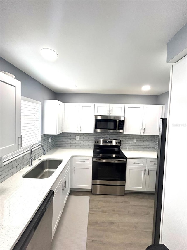 kitchen featuring decorative backsplash, white cabinets, light hardwood / wood-style flooring, sink, and stainless steel appliances