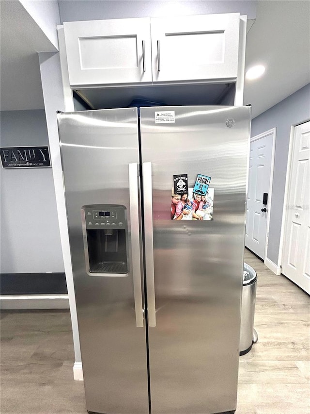 kitchen featuring white cabinets, light wood-type flooring, and stainless steel refrigerator with ice dispenser