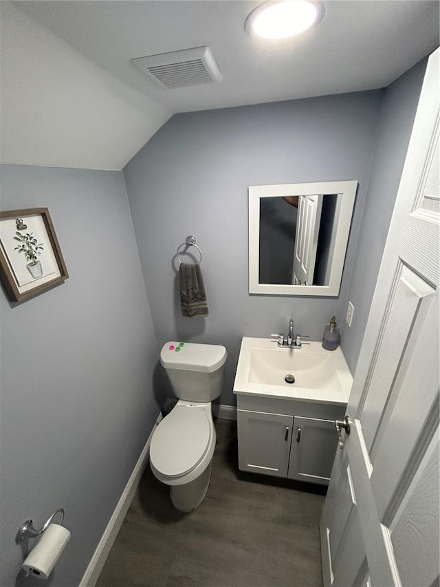 bathroom featuring vanity, toilet, lofted ceiling, and hardwood / wood-style floors