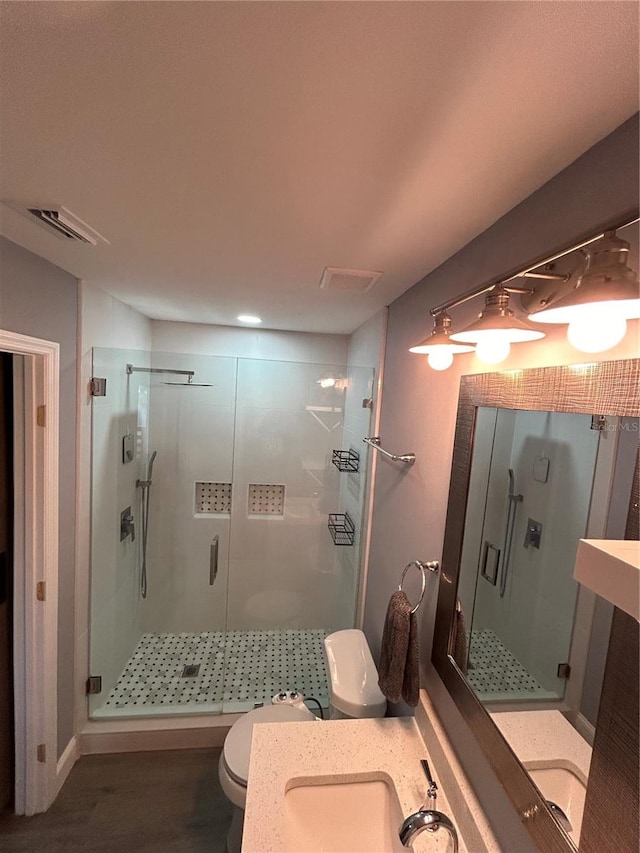 bathroom with vanity, a shower with shower door, hardwood / wood-style flooring, and toilet