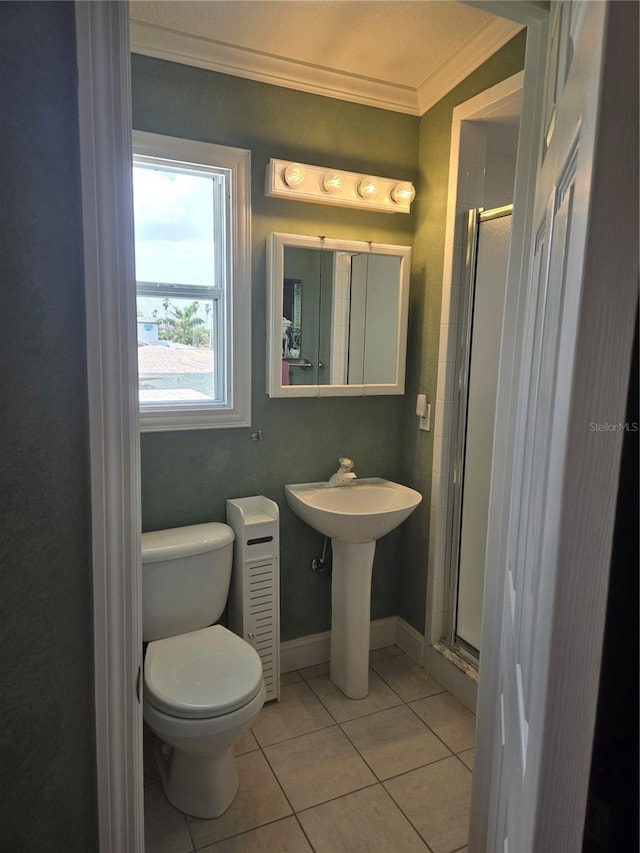 bathroom with tile patterned floors, ornamental molding, a shower with shower door, and toilet