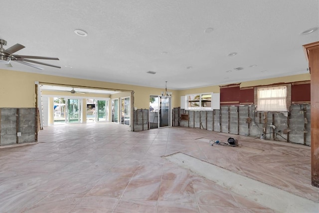 empty room with ceiling fan, light tile patterned floors, and a textured ceiling