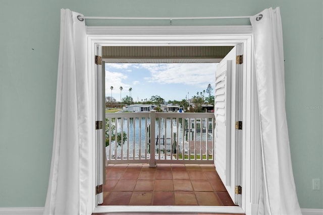 doorway to outside with tile patterned floors and a water view