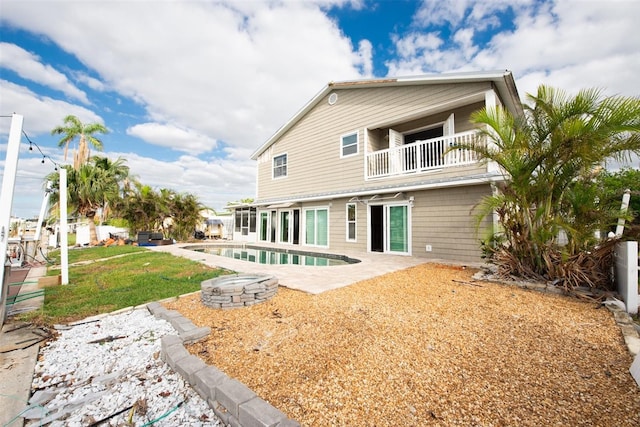 back of property with a yard, a balcony, and a patio area