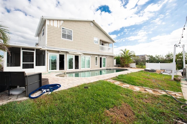 rear view of property featuring a sunroom, a yard, and a patio