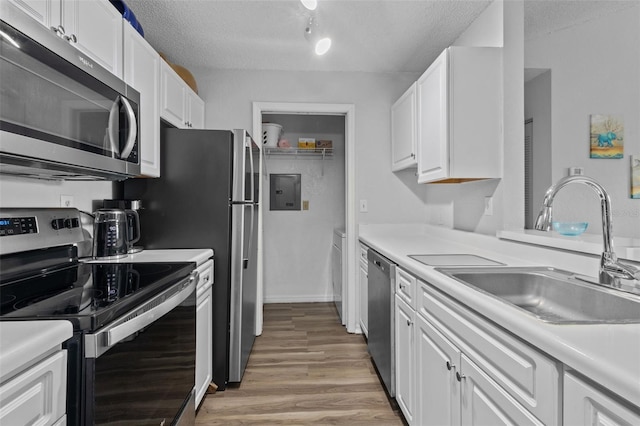 kitchen featuring appliances with stainless steel finishes, a textured ceiling, white cabinetry, and light hardwood / wood-style floors