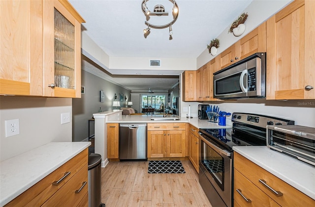 kitchen with light hardwood / wood-style floors, stainless steel appliances, sink, and kitchen peninsula