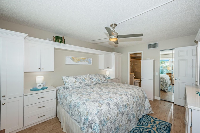 bedroom featuring ensuite bath, a textured ceiling, light wood-type flooring, and ceiling fan