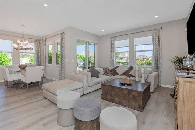 living room featuring light wood-type flooring, a chandelier, and plenty of natural light