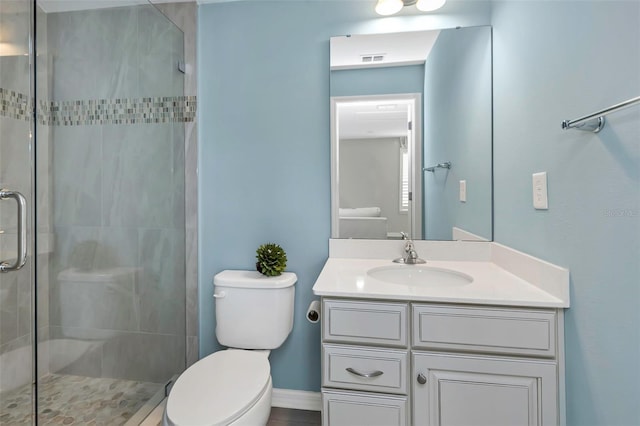 bathroom featuring a shower with door, vanity, and toilet