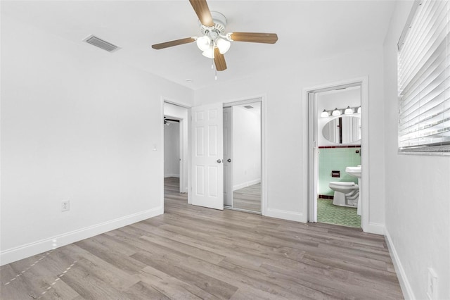 unfurnished bedroom featuring light hardwood / wood-style flooring, ceiling fan, and ensuite bath