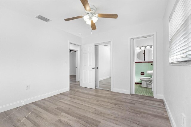 404 E Morgan St, Brandon, FL 33510 - unfurnished bedroom with wood finished floors, ceiling fan, ensuite bath, and baseboards