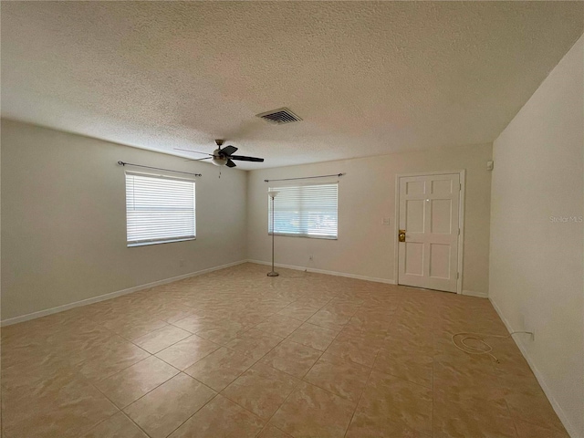 tiled spare room with ceiling fan and a textured ceiling