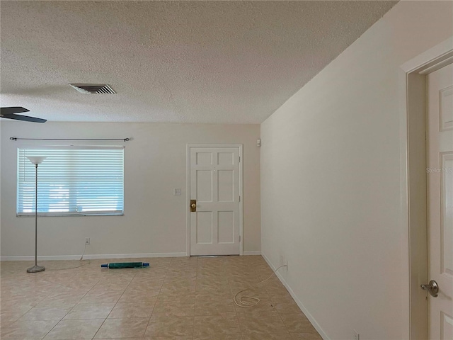 foyer with a textured ceiling, light tile patterned floors, and ceiling fan