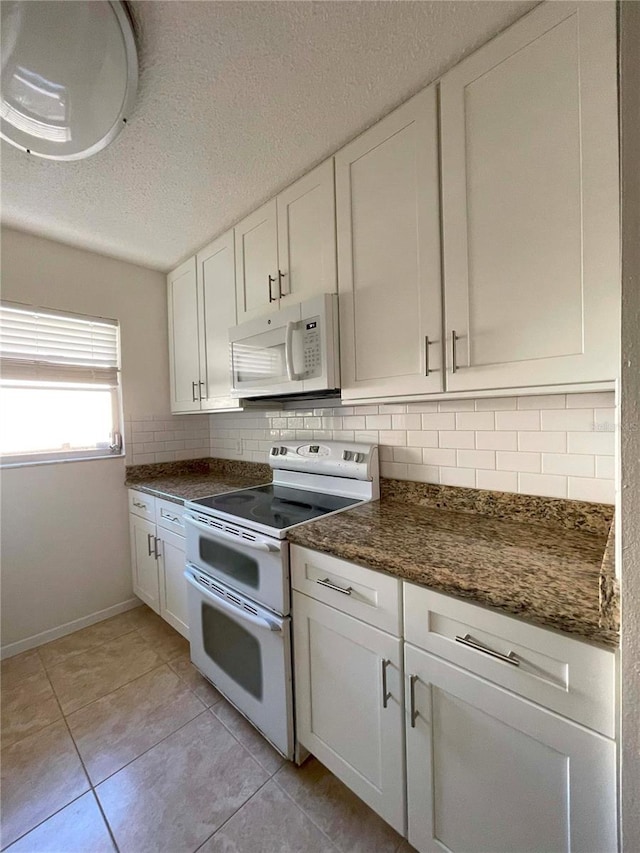 kitchen featuring white cabinets, dark stone counters, white appliances, and tasteful backsplash