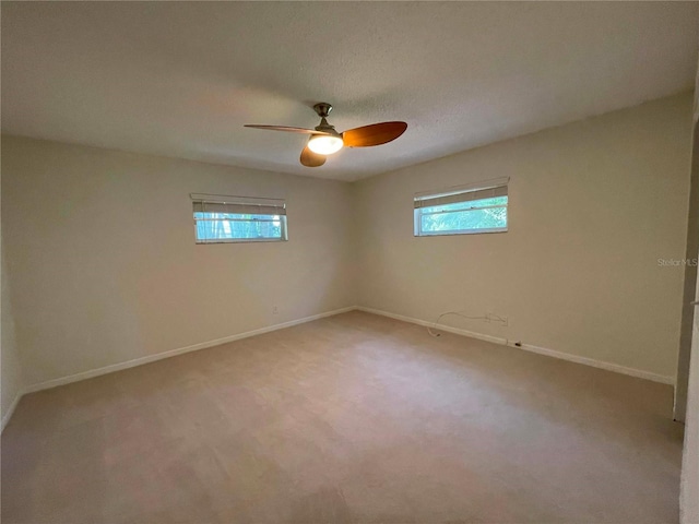 spare room with a wealth of natural light, carpet flooring, and ceiling fan