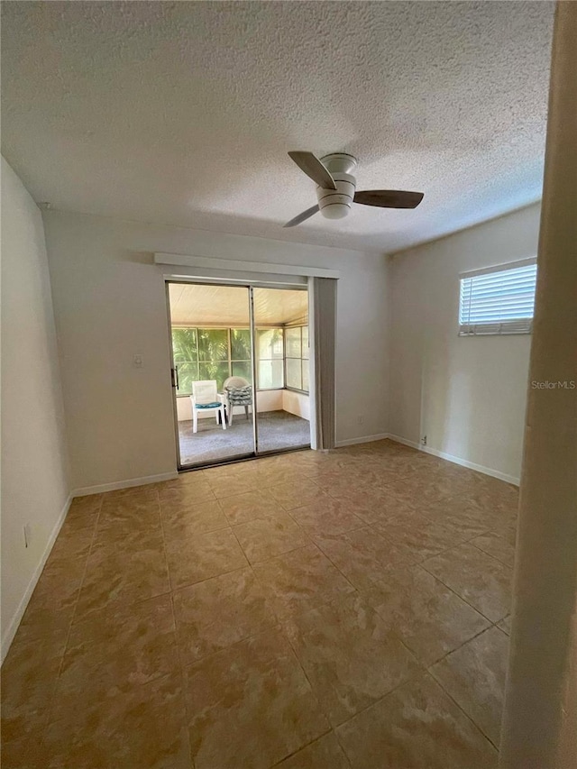 unfurnished room with a wealth of natural light, tile patterned floors, a textured ceiling, and ceiling fan