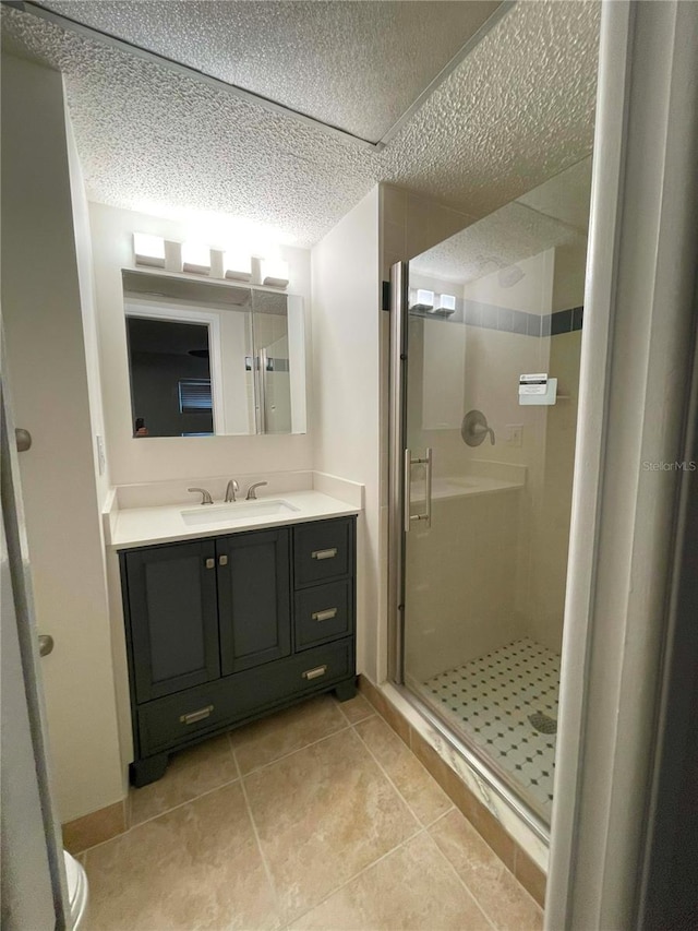 bathroom with vanity, a textured ceiling, tile patterned flooring, and an enclosed shower