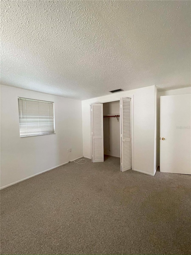 unfurnished bedroom with a closet, carpet, and a textured ceiling