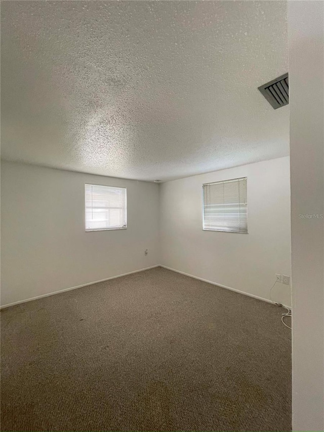 basement featuring a textured ceiling and dark carpet