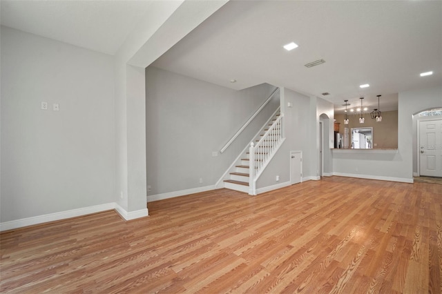 unfurnished living room with a chandelier and light wood-type flooring