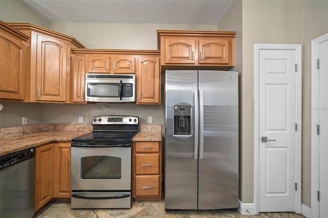 kitchen with a textured ceiling, light stone countertops, and stainless steel appliances