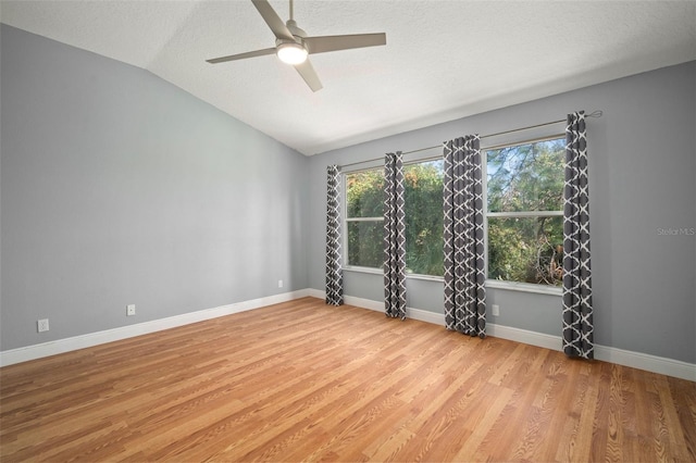 unfurnished room featuring vaulted ceiling, a textured ceiling, light hardwood / wood-style floors, and ceiling fan