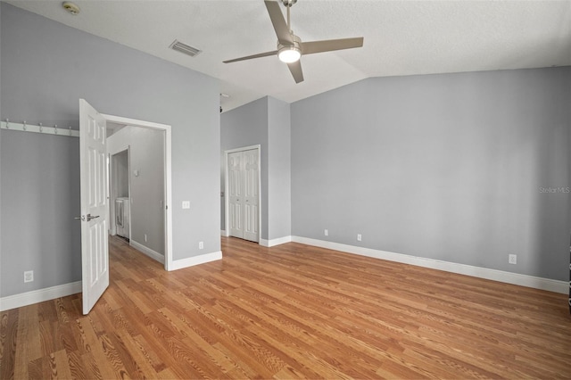 unfurnished bedroom with ceiling fan, a textured ceiling, vaulted ceiling, and light wood-type flooring