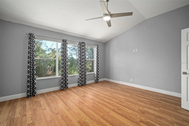 spare room with lofted ceiling, a textured ceiling, light wood-type flooring, and ceiling fan