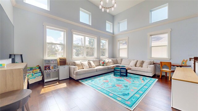 living room with a high ceiling, a notable chandelier, and dark hardwood / wood-style flooring