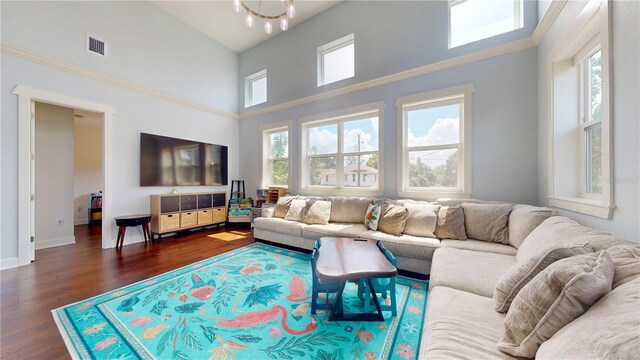 living room with a notable chandelier, high vaulted ceiling, a wealth of natural light, and dark hardwood / wood-style flooring