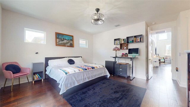 bedroom with a notable chandelier and dark hardwood / wood-style floors