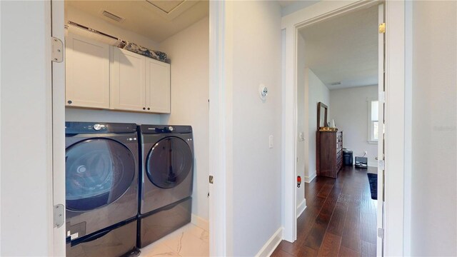 washroom with dark wood-type flooring, cabinets, and washer and clothes dryer