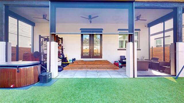 exterior space featuring a hot tub, french doors, a lawn, and ceiling fan