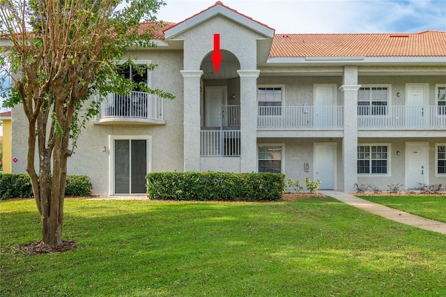 view of front facade featuring a balcony and a front yard