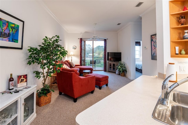 carpeted living room with ornamental molding, sink, and ceiling fan