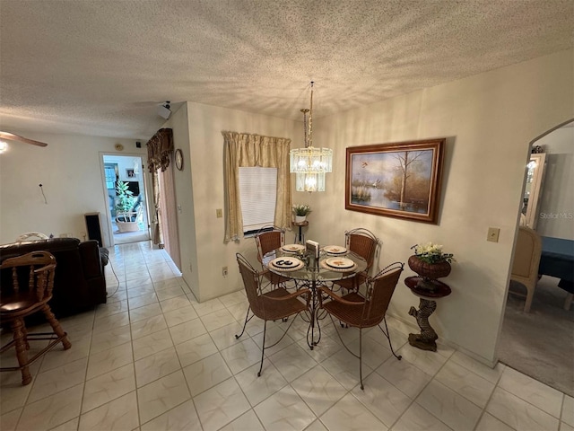 dining area featuring ceiling fan with notable chandelier and a textured ceiling