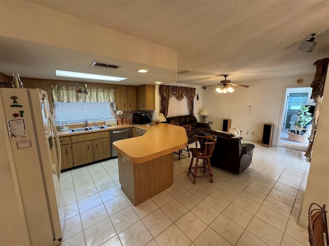 kitchen with dishwasher, white refrigerator with ice dispenser, sink, ceiling fan, and kitchen peninsula