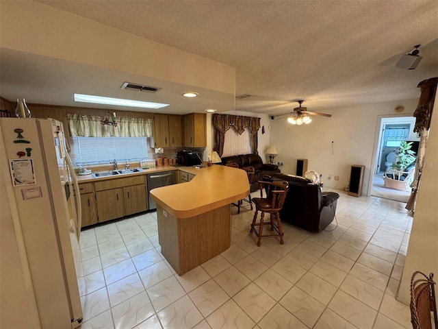 kitchen featuring a sink, light countertops, freestanding refrigerator, a peninsula, and marble finish floor