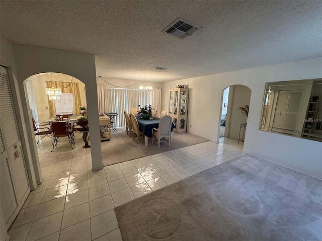 carpeted dining area featuring a textured ceiling and an inviting chandelier