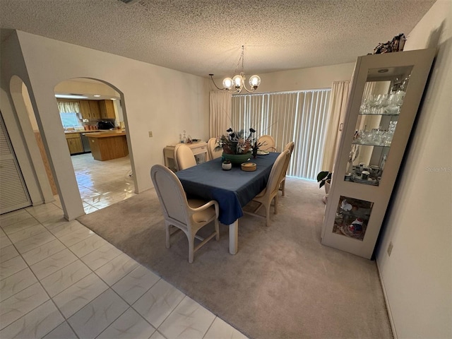 dining area featuring a notable chandelier, a textured ceiling, and light carpet