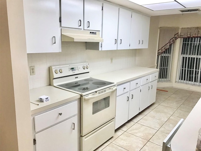 kitchen featuring white cabinetry, electric range oven, light tile patterned floors, and backsplash