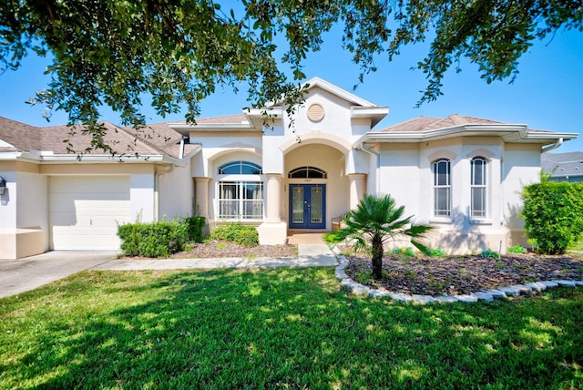 mediterranean / spanish-style house featuring a garage, a front yard, and french doors