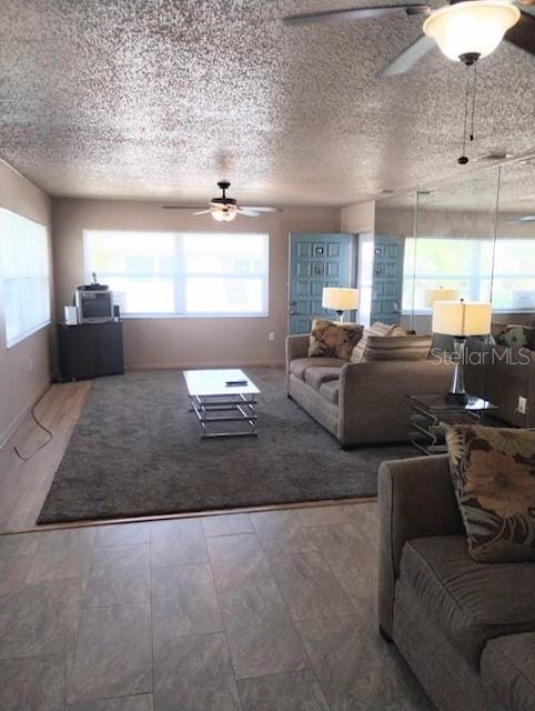 living room featuring ceiling fan and a textured ceiling