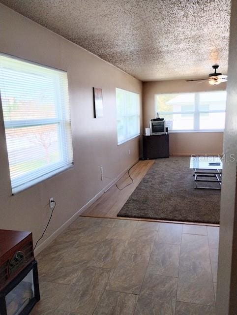 interior space with a textured ceiling, wood-type flooring, and ceiling fan